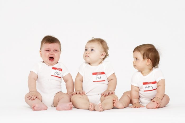 Three babies (6-9 months) sitting on white background, one crying