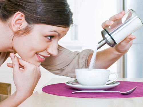 Женщина насыпает сахар в чай