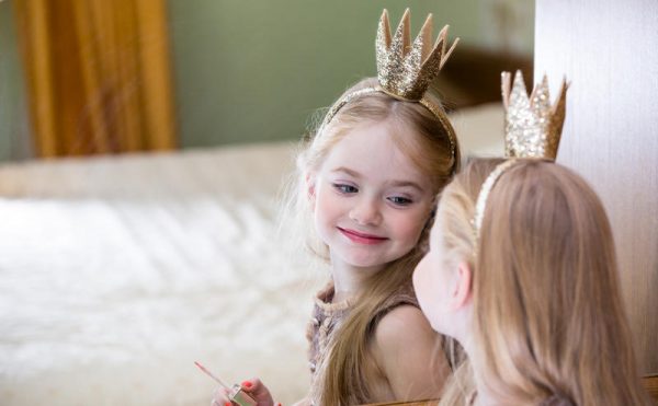 Девочка с короной любуется на себя в зеркало