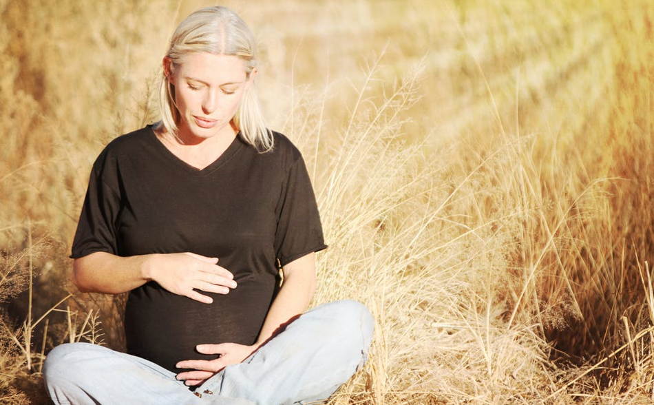 беременная женщина сидит в поле