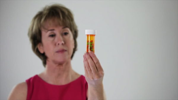 Женщина смотрит на таблетки